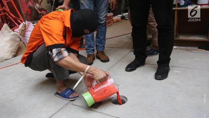 Seorang tersangka membuang barang hukti pil ekstasi yang sudah dimusnahkan menggunakan blender di Polda Metro Jaya, Jakarta, Jumat (20/7). Modus dalam pengungkapan narkoba jaringan internasional ini adalah pengiriman paket. (Liputan6.com/Arya Manggala)