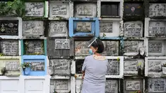 Seorang wanita berdoa di depan makam seorang kerabat di sebuah pemakaman di Manila, Filipina (28/10/2021). Pemerintah setempat akan menutup pemakaman nasional untuk Hari Semua Orang Kudus karena pandemi virus corona Covid-19. (AFP/Ted Aljibe)