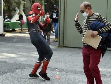 Seseorang yang mengenakan kostum Spiderman menyapa pria setelah disuntik vaksin covid-19 Pfizer-BioNTech di Mexico City, Meksiko, Selasa (28/12/2021). Spiderman tersebut dipekerjakan oleh Pemerintah Kota untuk menghibur para peserta vaksinasi. (ALFREDO ESTRELLA / AFP)