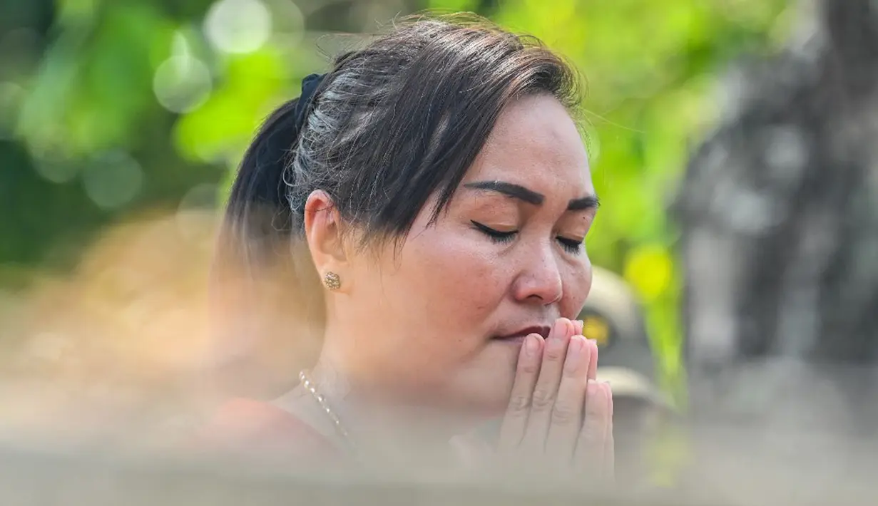 Tradisi ini diisi dengan kegiatan membersihkan makam, membakar dupa, uang arwah, serta memanjaatkan doa di depan nisan. (CHAIDEER MAHYUDDIN/AFP)
