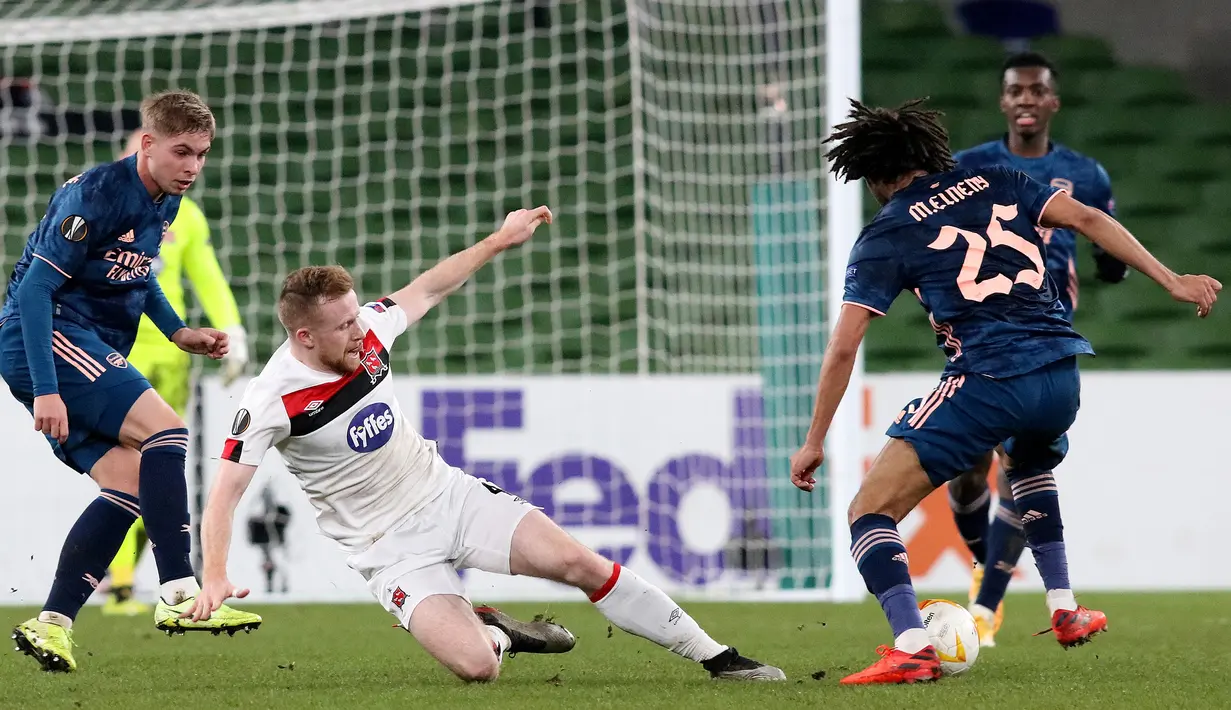 Gelandang Arsenal, Mohamed Elneny, berebut bola dengan bek Dundalk, Andy Boyle, pada laga lanjutan Liga Europa 2020/2021 di Aviva Stadium, Jumat (11/12/2020) dini hari WIB. Arsenal menang 4-2 atas Dundalk. (AFP/Paul Faith)