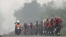 Di tengah pekatnya kabut asap, para pebalap terus melaju ke finis Etape 3 Tour de Singkarak 2015 di Dharmasraya, Sumatra Barat, Senin (5/10/2015). (Bola.com/Arief Bagus)