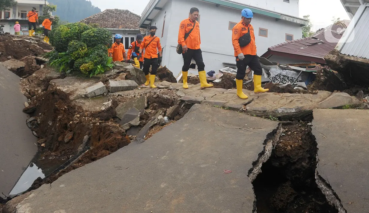 Petugas melintas di jalan yang rusak  pascagempa bumi magnitudo 5,6 di Kampung Cisarua, Desa Sarampad, Kabupaten Cianjur, Jawa Barat, Rabu (23/11/2022). Berdasarkan data BNPB sebanyak 58.362 warga mengungsi akibat gempa bumi di Kabupaten Cianjur tersebut. (merdeka.com/Arie Basuki)