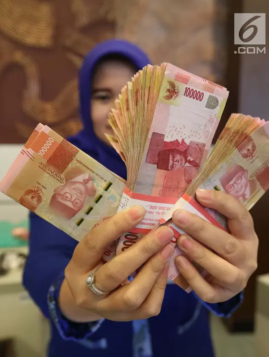 Petugas menunjukkan uang kertas rupiah di Bank BUMN, Jakarta, Selasa (17/4). Mengacu data Bloomberg, rupiah siang ini pukul 12.00 WIB di pasar spot exchange sebesar Rp 13.775 per dolar AS atau menguat 4,7 poin. (Liputan6.com/Angga Yuniar)
