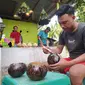 Eman Gani sedang membuat kerajinan tempurung kelapa di rumahnya di Kelurahan Bulotadaa Timur, Kecamatan Sipatana, Kota Gorontalo. (Liputan6.com/ Arfandi Ibrahim)