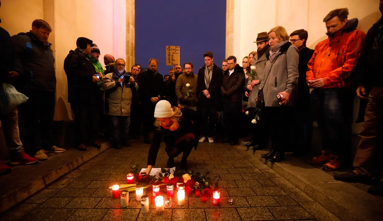 Seorang wanita meletakkan lilin saat berkabung untuk para korban penembakan brutal di Hanau di Gerbang Brandenburg Berlin, Jerman, Kamis (20/2/2020). Tersangka penembakan diketahui bernama Tobias R (43) yang diduga memiliki 'pola pikir yang sangat rasis'. (AP Photo/Markus Schreiber)