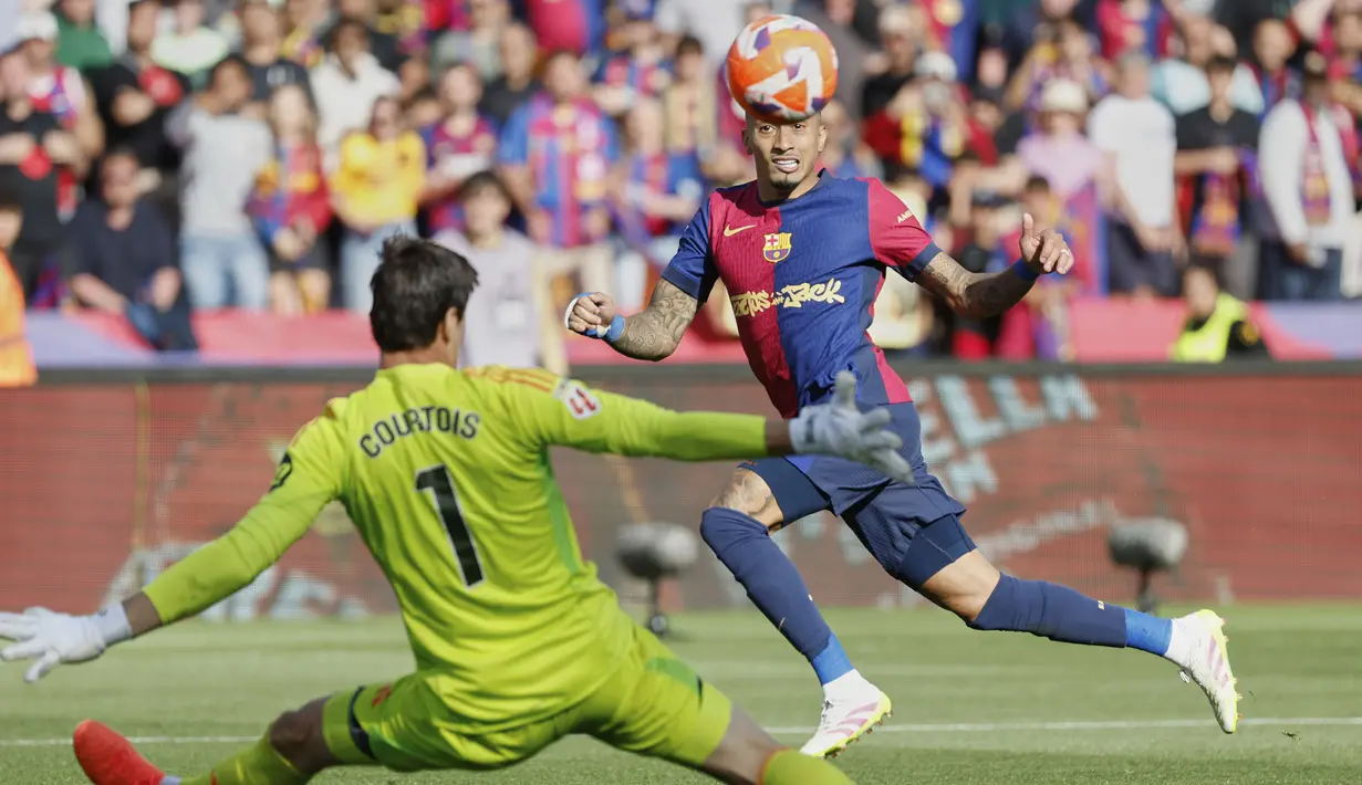 Pemain Barcelona, Raphinha mencetak gol ke gawang Real Madrid yang dijaga Thibaut Courtois dalam laga lanjutan Liga Spanyol 2024/2025 di Estadi Olimpic Lluis Companys, Barcelona, Spanyol, Minggu (11/05/2025) waktu setempat. (AP Photo/Jose Breton)