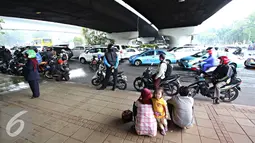 Sejumlah orang saat berteduh di bawah flyover saat hujan turun, Jakarta, Senin (16/11). Memasuki musim hujan, polisi meminta pengendara untuk tidak berteduh di sembarang tempat, khususnya di bawah fly over. (Liputan6.com/Immanuel Antonius)