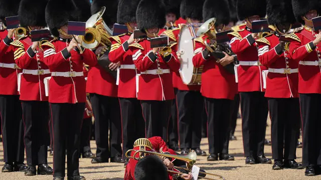 Seorang pemain trombone dari band militer pingsan saat Colonel's Review, latihan terakhir yang dilakukan untuk acara Trooping the Colour. (AP/Alberto Pezalli)