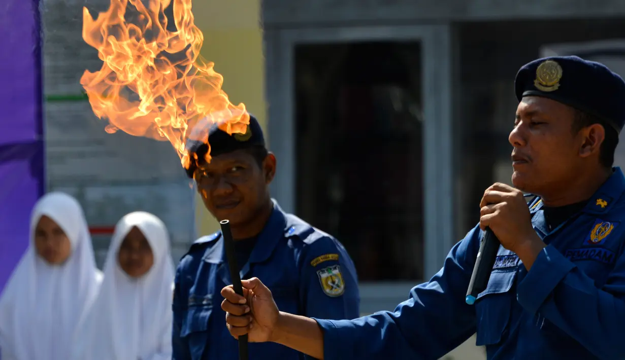Petugas pemadam kebakaran mengajarkan para siswa cara memadamkan api, Banda Aceh, Senin (11/11/2019). Sebanyak 439 pelajar mendapat pembekalan cara pencegahan pemadaman api akibat kebakaran dari petugas Dinas Pemadam Kebakaran dan Penyelamatan Kota Banda Aceh. (CHAIDEER MAHYUDDIN/AFP)