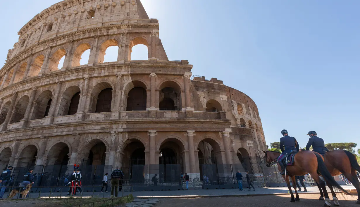 Polisi (kanan) dan petugas Carabinieri berpatroli di luar Colosseum di Roma, Italia, Senin (1/6/2020). Colosseum, yang merupakan ikon kota Roma dibuka kembali untuk umum pada Senin (1/6), setelah ditutup lebih dari dua bulan, dengan beberapa pembatasan akses bagi pengunjung. (AP/Domenico Stinellis)