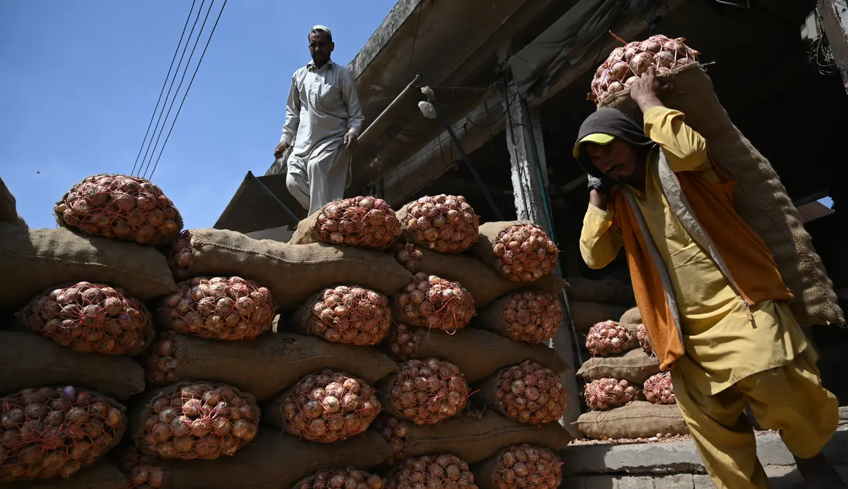 Seorang buruh Pakistan membawa sekarung bawang di sebuah pasar grosir sayuran di Islamabad (9/4). Islamabad dibangun pada 1960-an untuk menggantikan Karachi sebagai ibu kota Pakistan. (AFP Photo/Aamir Qureshi)