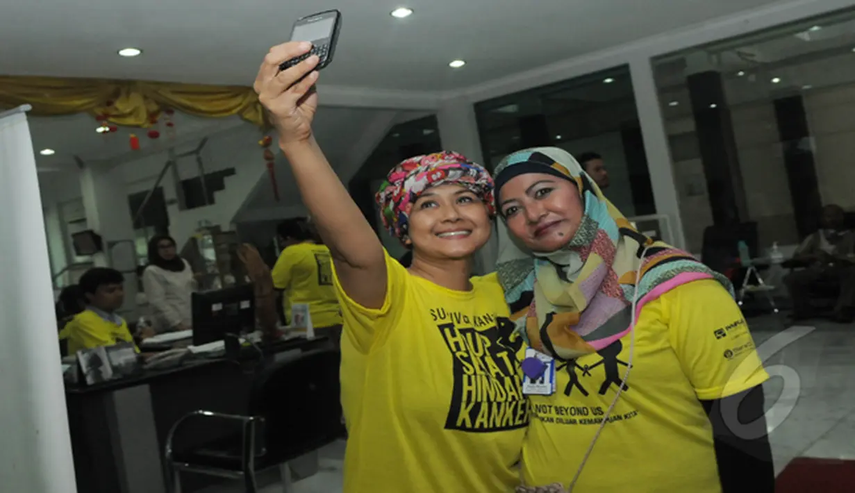Ria Irawan berfoto selfie dengan salah satu panitia penyelenggara Hari Kanker di RSCM, Jakarta, Rabu (4/2/2015). (Liputan6.com/Herman Zakharia)