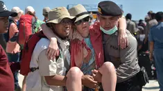 Petugas kepolisian dan penyelamat membantu turis asing yang dievakuasi dari Gili Trawangan saat tiba di Pelabuhan Bangsal, Lombok Utara, NTB, Selasa (7/8). Ribuan turis asing dievakuasi dari Gili Trawangan setelah gempa Lombok. (ADEK BERRY/AFP)