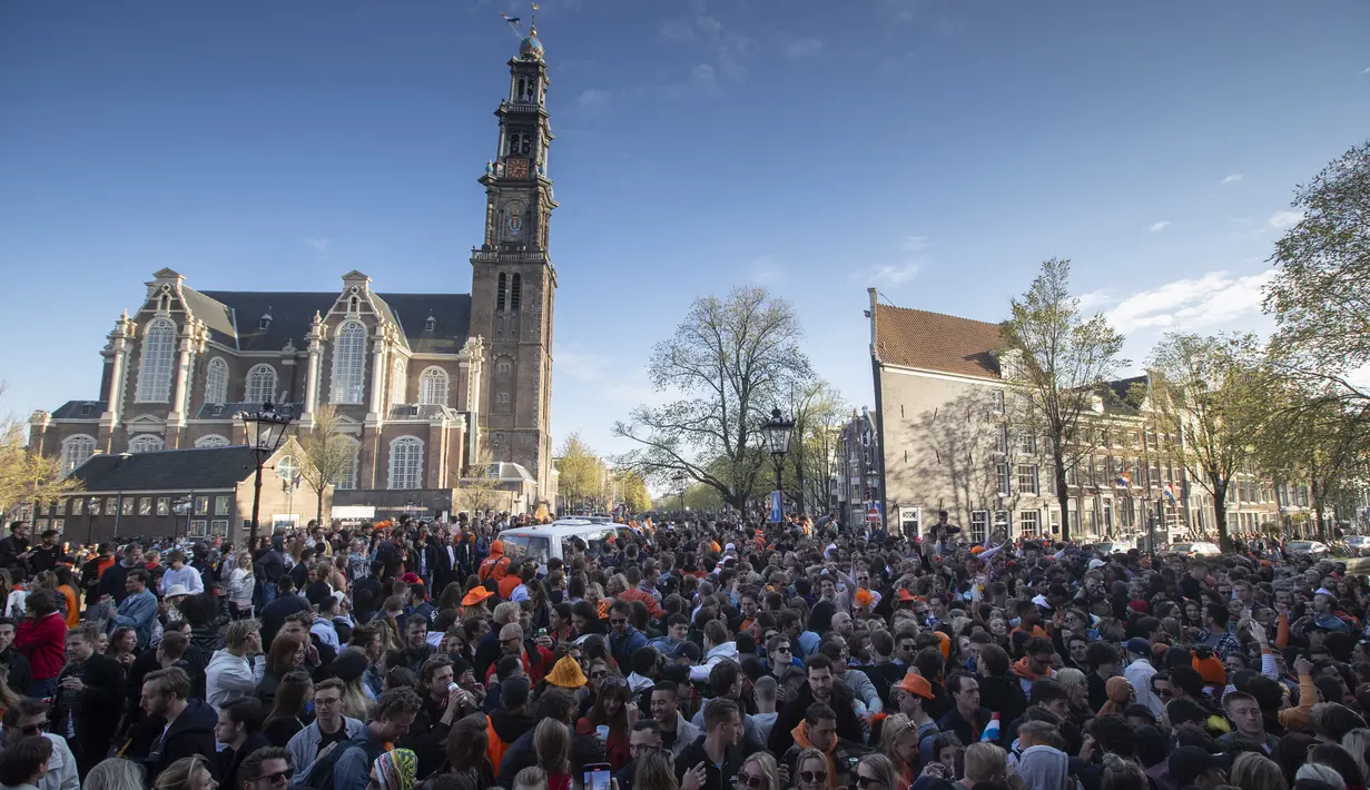 Warga merayakan Hari Raja dekat Gereja Westerkerk (belakang) di pusat Kota Amsterdam, Belanda, Selasa (27/4/2021). Pihak berwenang mendesak warga untuk tetap berpegang pada peraturan jarak sosial COVID-19. (AP Photo/Peter Dejong)