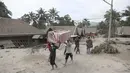 Warga membawa barang bawaannya saat mengungsi ke tempat yang lebih aman pasca erupsi Gunung Semeru di Kabupaten Lumajang, Provinsi Jawa Timur, Minggu (5/12/2021). (AP Photo/Trisnadi)