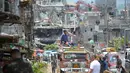 Warga mengambil gambar bangunan yang hancur dari atas mobil saat memasuki Kota Marawi, Mindanao, Filipina, Minggu (1/4). Mereka hampir setahun mengungki akibat pertempuran militer Filipina dengan militan ISIS. (TED ALJIBE/AFP)