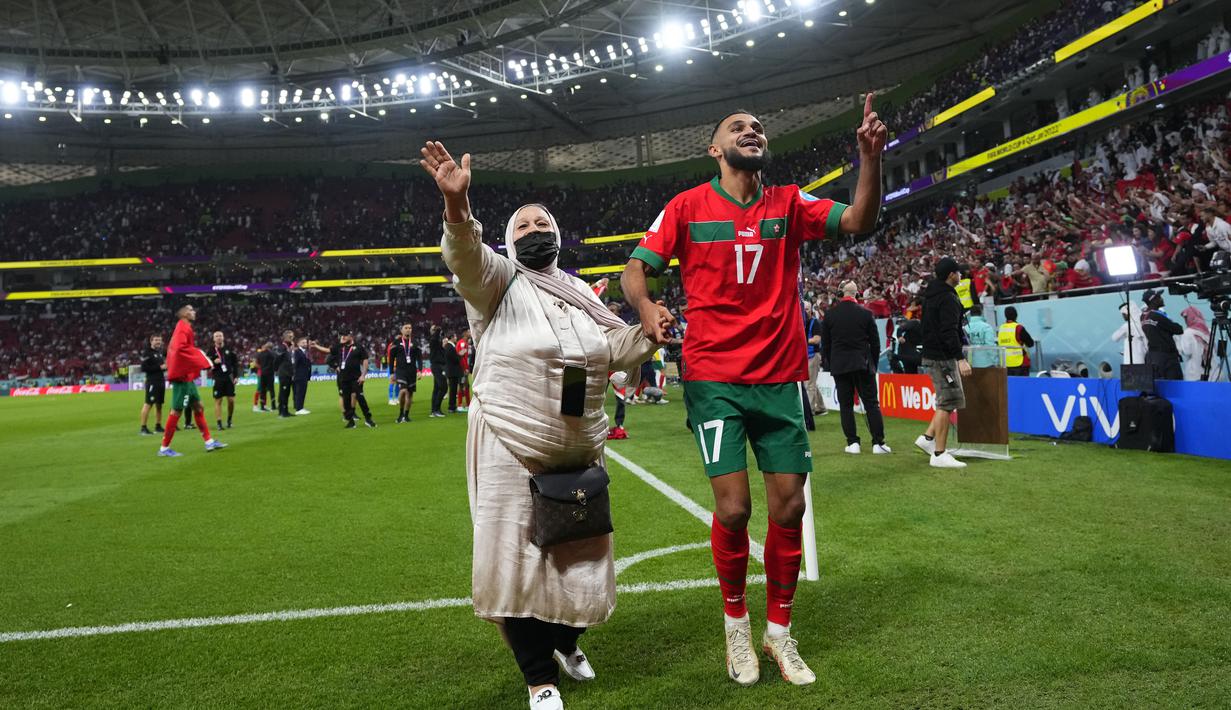 Pemain Maroko, Sofiane Boufal, merayakan kemenangan atas Portugal bersama keluarganya pada laga perempat final di Stadion Al-Thumama, Sabtu (10/12/2022). (AP/Petr David Josek)
