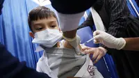 Seorang anak laki-laki menerima dosis vaksin covid-19 Pfizer-BioNTech di pusat vaksinasi di Kuwait International Fairground di Kuwait City pada 3 Februari 2022. Kementerian kesehatan Kuwait mulai memvaksinasi anak usia 5 hingga 11 tahun. (YASSER AL-ZAYYAT / AFP)