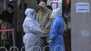 Petugas medis berbaju pelindung saling mengobrol saat warga menunggu masuk ke klinik demam sebuah rumah sakit di Beijing, Selasa (13/12/2022). Beberapa universitas di China mengatakan akan mengizinkan mahasiswanya menyelesaikan semester dari rumah dengan harapan mengurangi potensi wabah COVID-19 yang lebih besar selama kesibukan perjalanan Tahun Baru Imlek di bulan Januari mendatang. (AP Photo/Andy Wong)