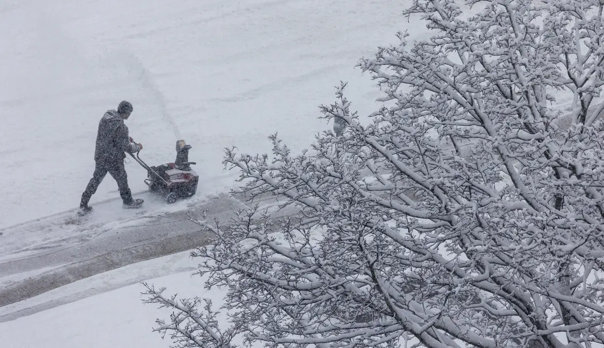 Seseorang membersihkan salju dari trotoar di luar Gedung Pengadilan Kalamazoo County di Kalamazoo, Michigan, Rabu (2/2/2022). Gubernur mendesak penduduk untuk menjauh dari jalan dan menutup sekolah dan kampus. (Joel Bissell/Kalamazoo Gazette via AP)