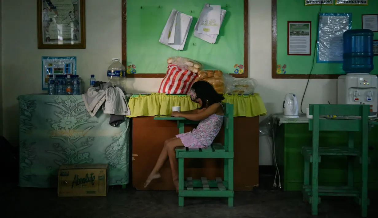 Seorang anak duduk di ruang kelas Sekolah Dasar Dona Tiburcia Carpio Malvar yang digunakan sebagai pusat evakuasi korban letusan Gunung Taal, Tanauan, Filipina, Rabu (16/1/2020). Pihak berwenang Filipina memperingatkan bahwa potensi Gunung Taal untuk kembali meletus masih tinggi. (Ed JONES/AFP)