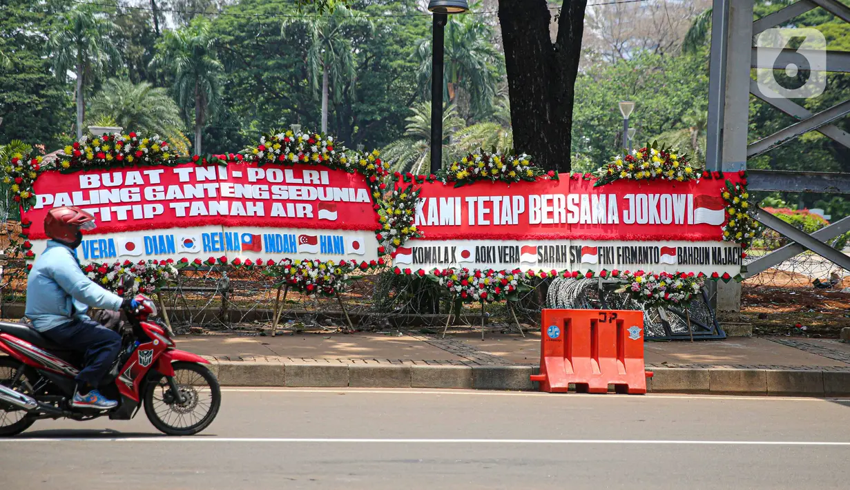Kendaraan melintasi karangan bunga yang menghiasi kawasan Patung Kuda, Jakarta, Kamis (15/10/2020). Karangan bunga tersebut merupakan apresiasi masyarakat kepada TNI-Polri yang telah menjaga keamanan saat demo. (Liputan6.com/Faizal Fanani)
