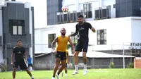 Julian Guevara menanduk bola dalam sesi latihan Arema FC sembari dibayangi Dalberto Luan dan Ikhsan Lestaluhu. (Bola.com/Iwan Setiawan)