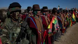 Tentara berbaris bersama pria Aymara menyanyikan lagu kebangsaan mereka saat pawai ulang tahun tentara Bolivia ke-192 di Kjasina, Bolivia (7/8). Hal ini unik dari upacara militer ini adalah karena digelar di tengah gurun. (AP Photo/Juan Karita)