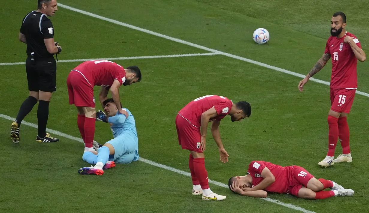 Reaksi kesakitan Majid Hosseini (kanan bawah) dan Alireza Beiranvand (kiri bawah) setelah bertabrakan saat pertandingan sepak bola grup B Piala Dunia Qatar 2022 antara Inggris dan Iran di Stadion Internasional Khalifa, Doha, Qatar, Senin (21/11/2022). Cedera ini disebabkan mulut sang kiper menghantam pipi Majid Hosseini rekan setimnya. (AP Photo/Pavel Golovkin)