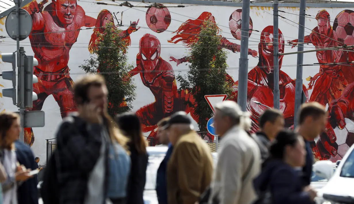 Ratusan fans melintas dekat mural Super Hero  Marvel Universe dekat Luzhniki stadium, Moskow, Rusia, (14/6/2018). Rusia akan melawan Arab Saudi pada laga pembuka. (AP/Pavel Golovkin)
