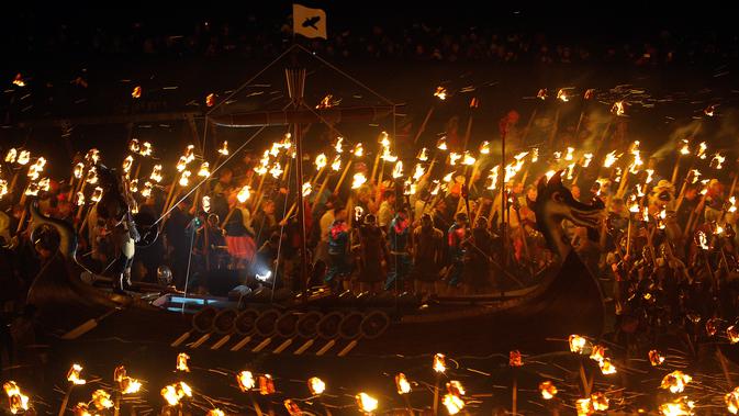 Sejumlah orang berpakaian seperti Viking mengelilingi kapal sambil membawa obor selama festival Up Helly Aa Viking di Lerwick, Kepulauan Shetland, Skotlandia (31/1). Hingga saat ini perayaan ini masih tetap digelar tiap tahunnya.(AFP/Andy Buchanan)