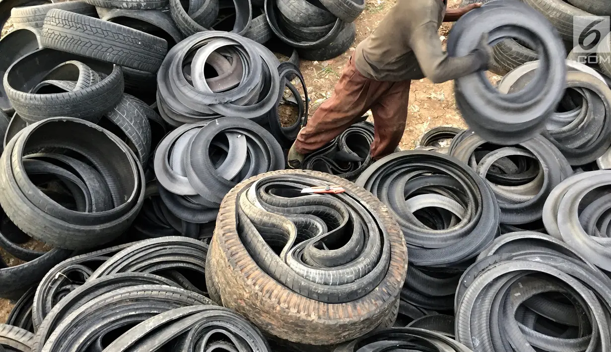 Pengepul memotong limbah ban bekas di kawasan Tanah Abang, Jakarta, Rabu (27/12). Keterbatasan lahan membuat para pengepul terpaksa mengumpulkan limbah ban bekas dari seluruh kawasan bantaran Kanal Banjir Barat. (Liputan6.com/Immanuel Antonius)