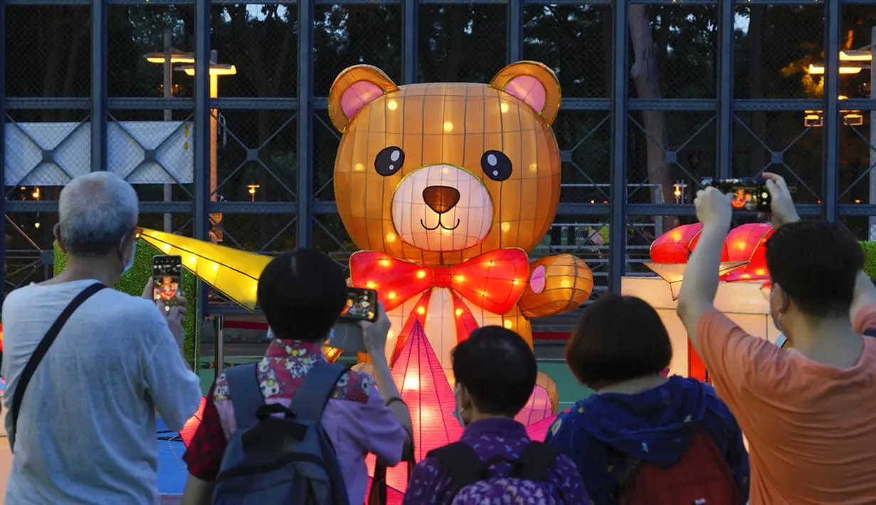 Orang-orang mengambil gambar dekorasi selama Festival Pertengahan Musim Gugur di taman Victoria di Hong Kong, Selasa (21/9/2021).  Festival ini jatuh pada hari ke-15 bulan ke-8 penanggalan Imlek. (AP Photo/Vincent Yu)