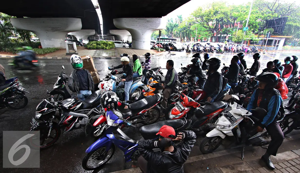 Pengendara sepeda motor berteduh di bawah flyover saat hujan turun, Jakarta, Senin (16/11). Petugas kepolisian akan menerapkan tilang dengan denda maksimal Rp250.000. (Liputan6.com/Immanuel Antonius)