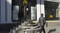 Seorang pria berjalan melewati restoran McDonald's yang tertutup untuk pengunjung di St. Petersburg, Rusia, Selasa (15/3/2022). Penutupan ini dilakukan pihak McDonald's sebagai sikap atas invasi Rusia ke Ukraina yang berlangsung dari 24 Februari 2022 lalu. (AP Photo)