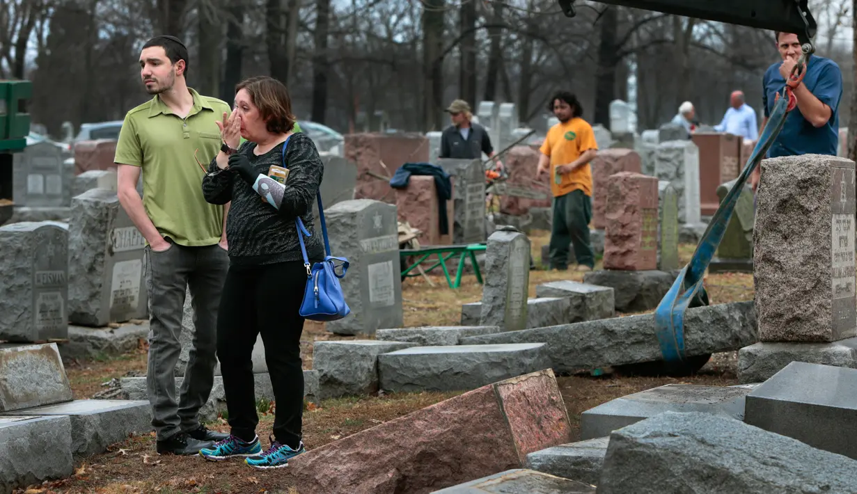 Sally Amon dan anaknya Max Amon saat melihat batu nisan neneknya yang dirusak usai mendapatkan serangan vandalisme di Chesed Shel Emeth Cemetery di University City, St Louis, Missouri, (21/2). (Robert Cohen /St. Louis Post-Dispatch via AP)