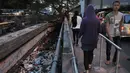 Tanpa memperdulikan bau sampah yang mulai menyengat, beberapa warga tetap melintasi jembatan kali Roxy, Jakarta, (9/8/2014). (Liputan6.com/Johan Tallo)