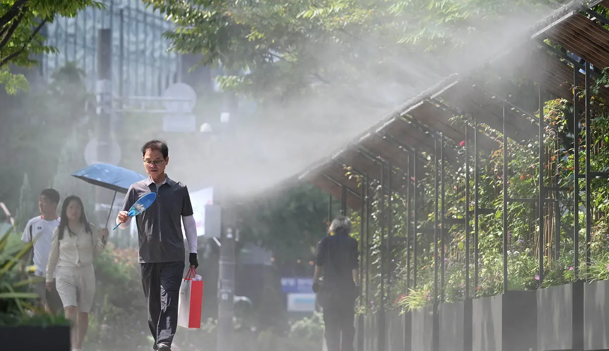 Orang-orang berjalan di zona penyemprotan kabut untuk mendinginkan diri di sebuah jalan di Seoul, Korea Selatan, Senin, 3 Agustus 2026. (AFP/  Jung Yeon-je)