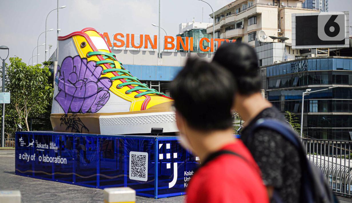 Pejalan kaki melintas di depan Tugu Sepatu, Sudirman, Jakarta, Minggu (19/9/2021). Tugu Sepatu menjadi sasaran pencoretan dengan semprotan aerosol oleh orang tak dikenal sehari usai diresmikan pada 17 September 2021. (Liputan6.com/Faizal Fanani)