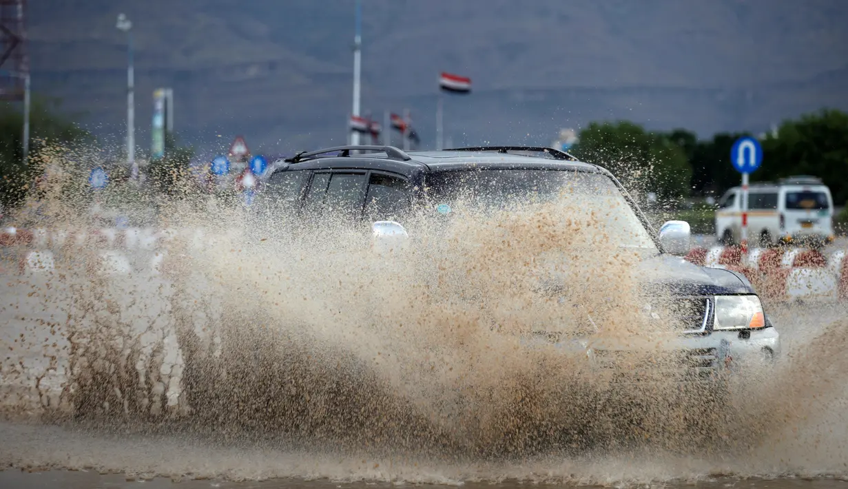 Sebuah mobil melintas di jalan yang terendam banjir di Sanaa, Yaman, (2/8). Hujan lebat yang mengguyur Sanaa membuat salah satu ruas jalan di kota itu berubah seakan menjadi sungai. (REUTERS / Khaled Abdullah)