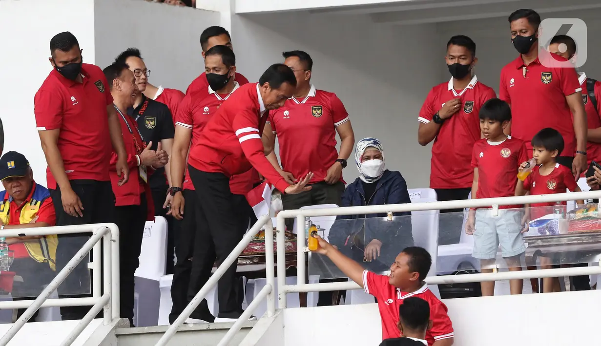 Presiden Joko Widodo (kedua kiri depan) saat memberi botol berisi minuman kepada salah satu supporter yang menyaksikan laga timnas Indonesia melawan Thailand pada lanjutan kualifikasi Grup A Piala AFF 2022 di Stadion Utama Gelora Bung Karno, Jakarta, Kamis (29/12/2022). Laga berakhir imbang 1-1 meski Indonesia sempat unggul lewat gol yang dicetak Marc Anthony Klok lewat titik putih. (Liputan6.com/Helmi Fithriansyah)