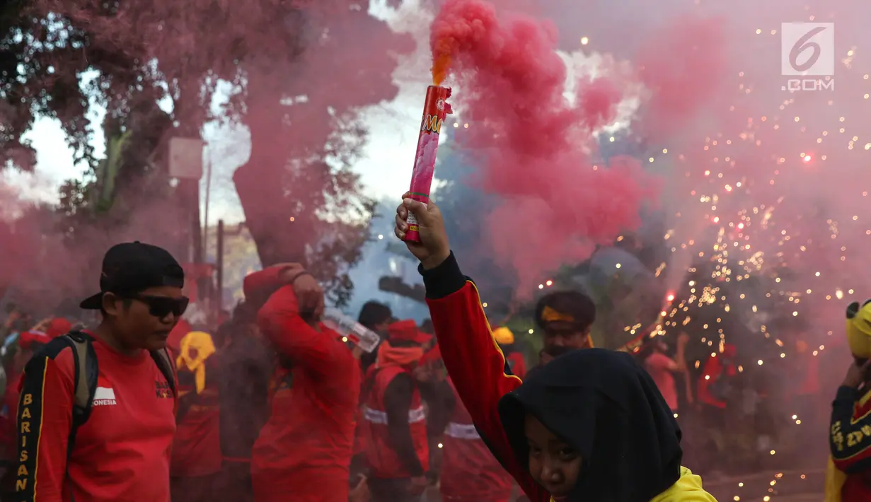 Sejumlah buruh menyalakan bom asap saat menutup aksi Hari Buruh Internasional di Jalan Medan Merdeka Barat, Jakarta, Rabu (5/1/2019). Buruh dari berbagai organisasi merayakan Hari Buruh Internasional di Kawasan Silang Barat Daya Monas. (Liputan6.com/Helmi Fithriansyah)