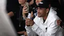 Pemain PSG, Neymar bermain ponsel saat menghadiri acara peragaan busana Off-White Spring-Summer 2019 Ready-to-Wear selama Paris Fashion Week, Prancis (27/9). Neymar tampil mengenakan jaket putih dan kaca mata emas. (AFP Photo/Francois Guillot)