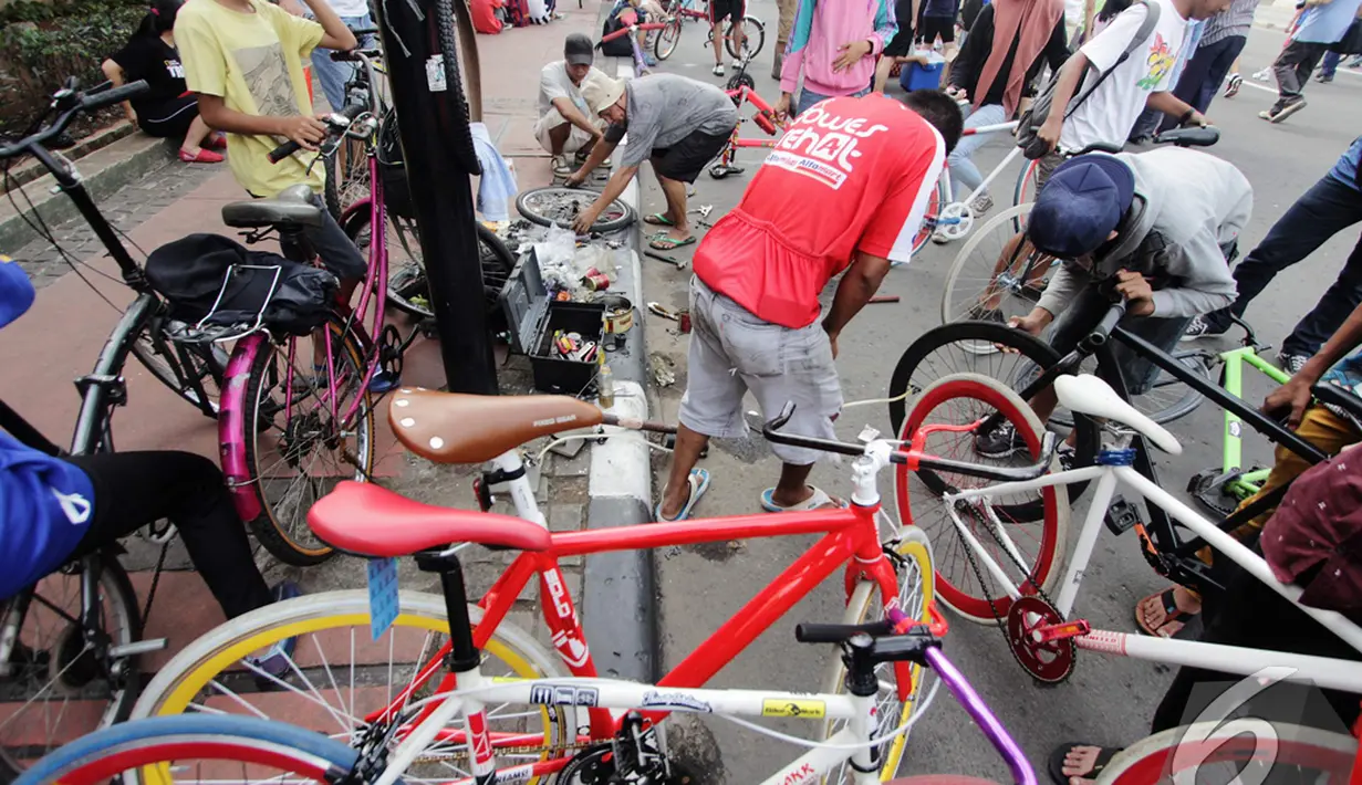 Suasana Car Free Day yang penuh dengan pejalan dan pengendara sepeda menjadi ladang uang untuk teknisi sepeda, kawasan Bundaran Hotel Indonesia, Jakarta, Minggu (14/12/2014). (Liputan6.com/Faizal Fanani)