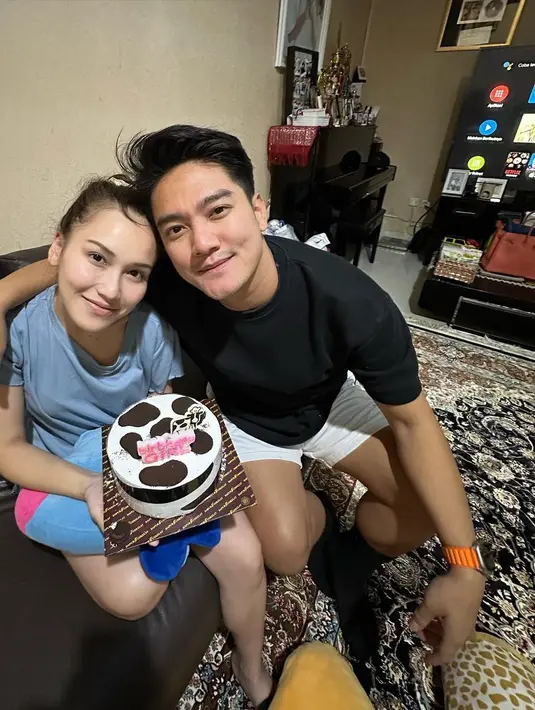 Foto yang tak kalah manis. Ayu Ting Ting dan Boy tampil sederhana dengan baju rumah. Ayu yang berulang tahun memegang kue mengenakan kaus biru muda, sedangkan Boy merangkulkan tangannya di pundak Ayu mengenakan kaus hitam dan celana pendek putih. [Foto: Instagram/boywilliam17]