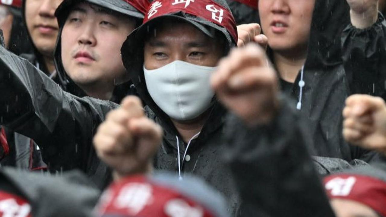 Dalam aksinya, ribuan buruh dengan mantel hitam dan ikat kepala merah berkumpul dan berbaris rapi di depan pabrik.&nbsp;Foto: Jung Yeon-je/AFP