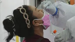 Seorang petugas kesehatan mengambil swab hidung seorang wanita untuk tes virus corona di sebuah pasar di Bangkok, Thailand, Jumat (11/6/2021). Thailand juga melaporkan 43 kematian baru akibat Covid-19 sehingga total kematian mencapai 1.375 orang sejak awal pandemi. (AP Photo/Sakchai Lalit)