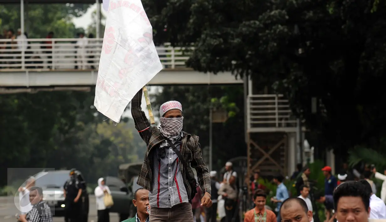 Massa aksi damai mengibarkan bendera di sekitar Bundaran Patung Arjuna Wijaya, Jakarta, Jumat (4/11). Massa berkumpul untuk melakukan aksi di depan Istana Negara menuntut penegakan hukum kasus dugaan penistaan agama. (Liputan6.com/Helmi Fithriansyah)