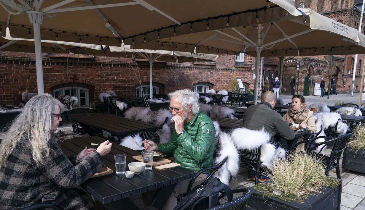 Orang-orang menerima layanan luar ruangan di sebuah kafe di Roskilde Denmark, pada Rabu (21/4/2021). Denmark mengizinkan diberlakukannya layanan indoor di restoran dan kafe mulai 21 April, lebih cepat dari yang diperkirakan sebelumnya. (Claus Bech/Ritzau Scanpix via AP)